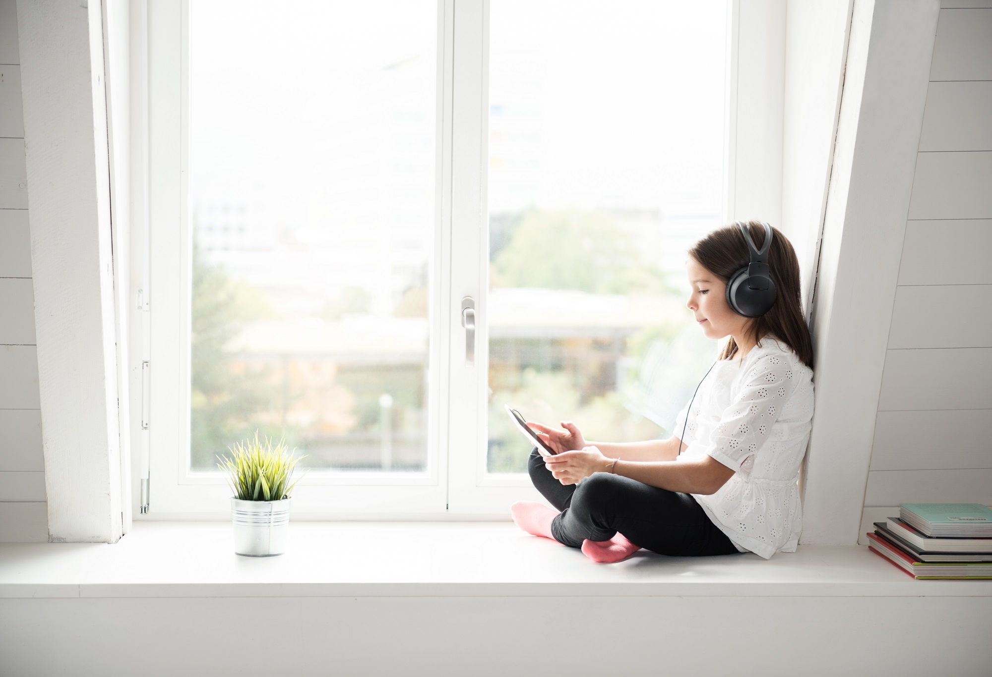 Child listening to music on window sill